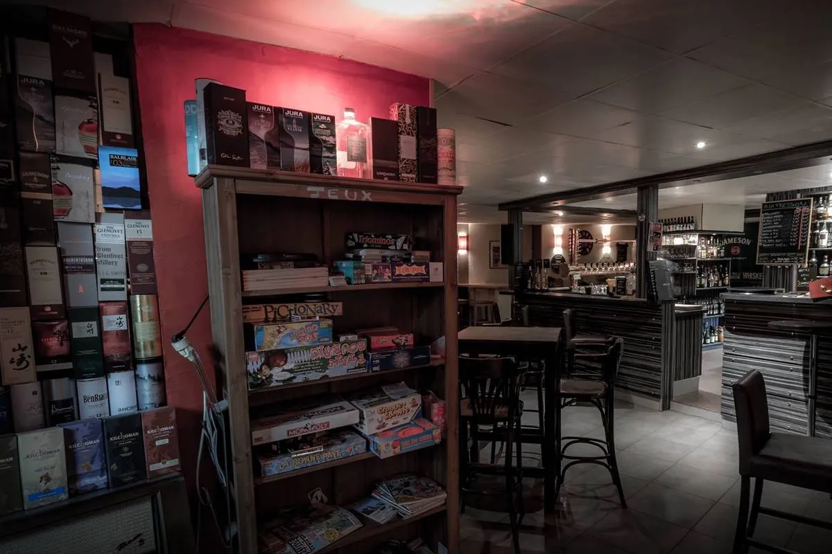 La salle, le mur de whiskys et l'étagère de jeux de société