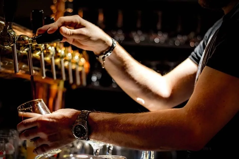 Un serveur tire une bière au comptoir de L'Intenable